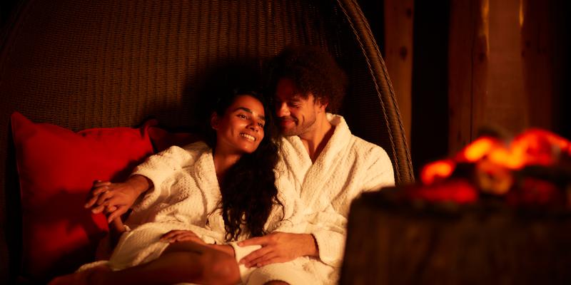 Relaxed couple sat by fire pit