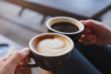 Two coffee mugs toasting.