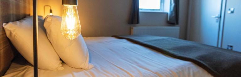 Cozy modern bedroom with a double bed, warm lighting, and soft furnishings creating a calm, inviting atmosphere.
